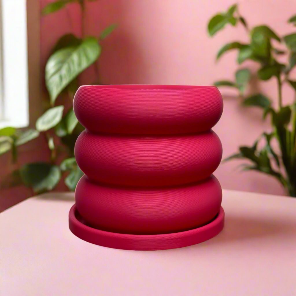 Bright pink Bubble Planter with drainage, resembling a whimsical stack of donuts, 3D-printed for plant lovers, available in multiple colors, sitting on a wooden surface, perfect for home decor.