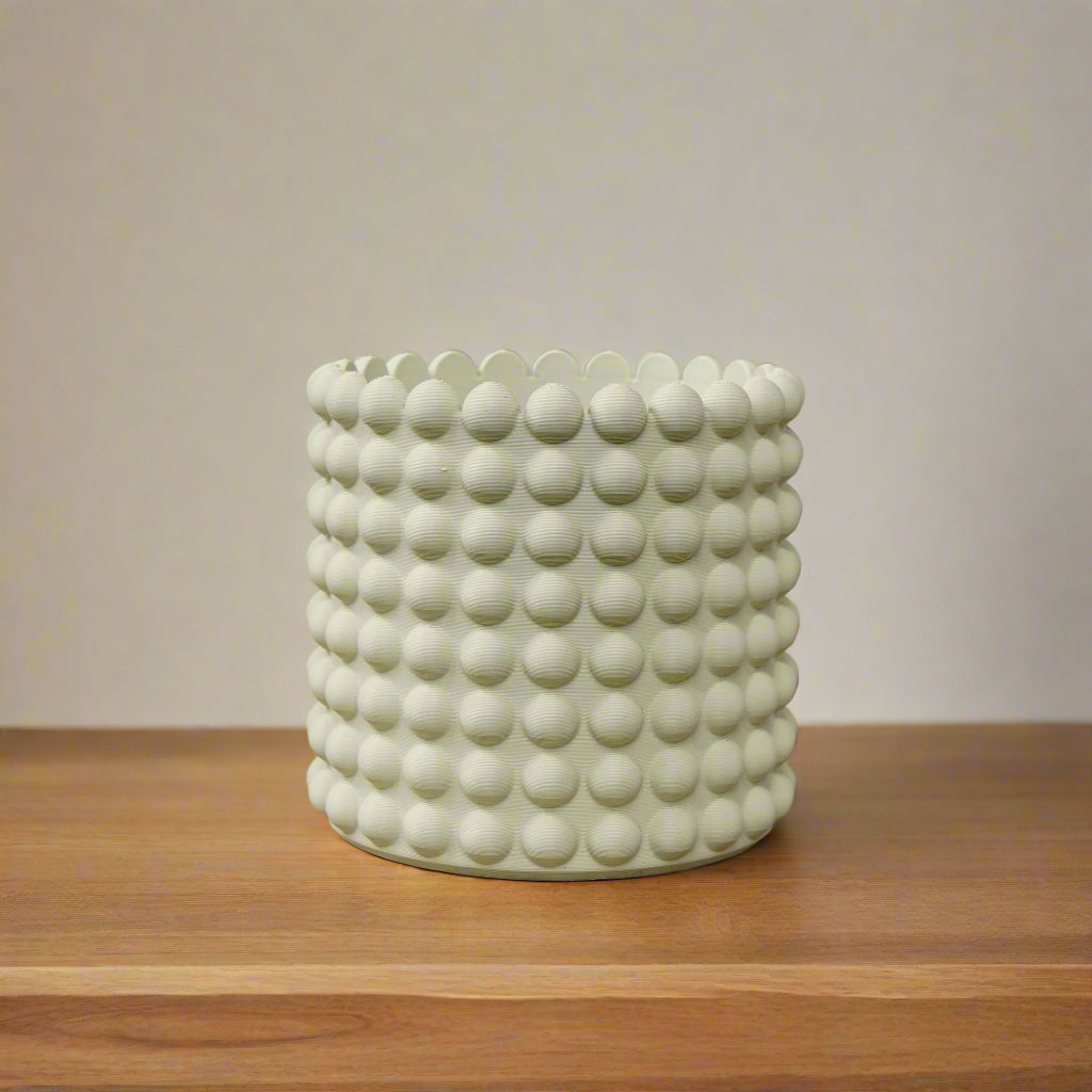 White textured ceramic pot on a wooden surface with a light green background