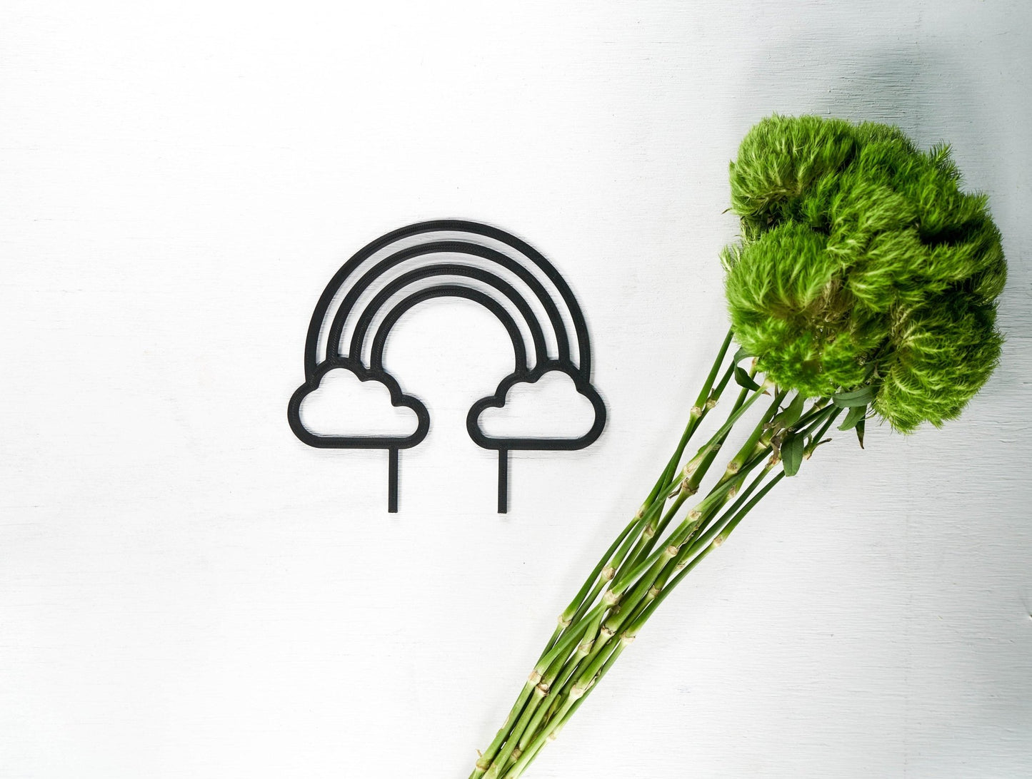 "Rainbow Plant Trellis in black, shaped like a rainbow with clouds at the bottom ends, a modern and elegant trellis designed to support climbing plants, made from eco-friendly and vegan-friendly 3D printed materials, perfect for plant lovers and home decor enthusiasts, offering excellent drainage and available in multiple colors, shown here with a vibrant green plant stem"